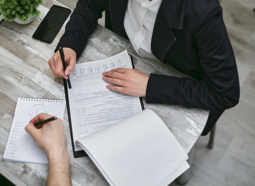 Two People Sitting at Desk with Documents