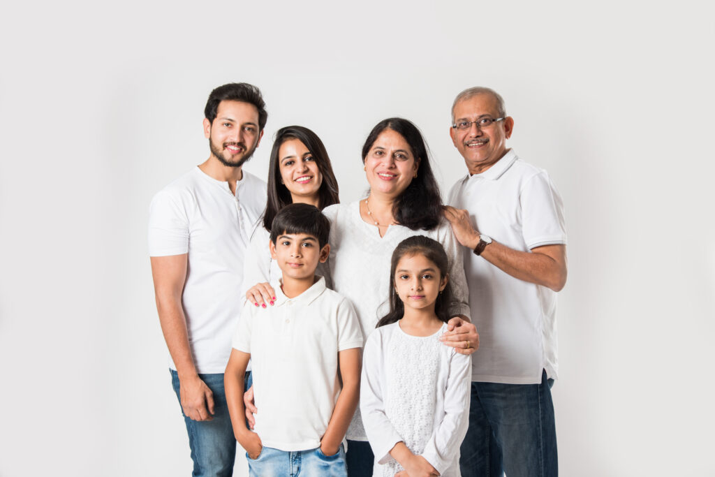 Indian family standing isolated over white background. senior and young couple with kids wearing white top and blue jeans. selective focus